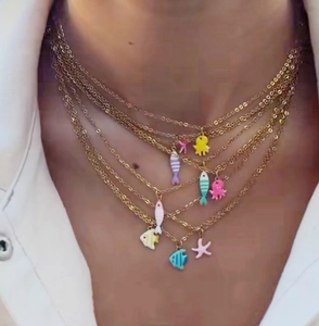 Detailed view of layered gold necklaces with enamel sea star and fish charms
