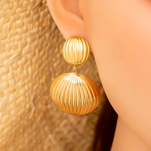 Elegante goldene ovale Ohrringe mit vertikalen Rillen an einem weiblichen Model