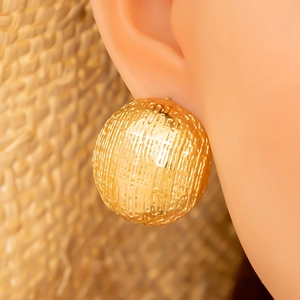 Detail eines goldenen Ohrrings mit Hammerschlag-Textur und hochglänzendem Metall-Finish