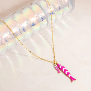 Detail of gold chain necklace with pink fish charms featuring white wave enamel patterns