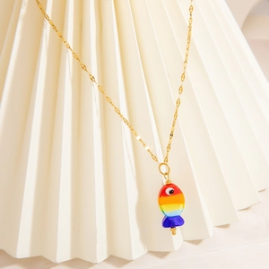 Macro detail of a colorful tropical fish pendant on a gold stainless steel chain
