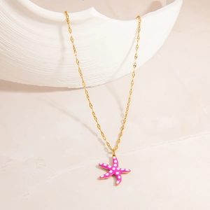Detailed view of handmade pink starfish pendant with white polka dots on 18K gold chain