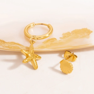 Detailed view of 18K gold starfish pendant and shell stud earrings on white ceramic