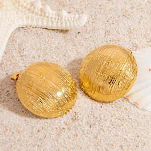 Detail von goldenen Muschelohrringen mit Wellenstruktur auf feinem Strandsand