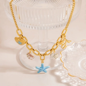 Collier doré thème océan avec pendentifs étoile de mer et corail sur décor d'été