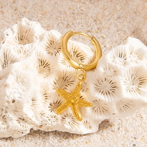 Gold stainless steel starfish charm earrings on coral reef with white beach sand background