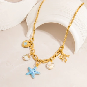Détails des breloques étoile de mer et corail sur un collier thème marin doré