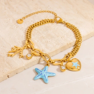 Détail d'un bracelet doré thème océan avec pendentifs étoile de mer, corail et cœur