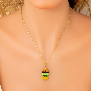 Close-up of a golden necklace with a colorful striped tropical fish pendant on a model
