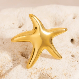 Polished 18K gold stainless steel starfish ring on white coral stone background