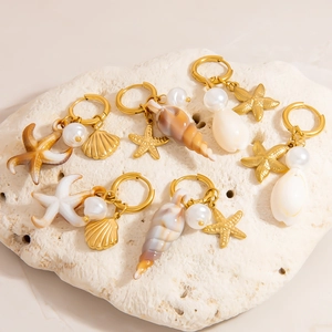 Set di orecchini dorati tema oceano con stelle marine, conchiglie e perle su corallo