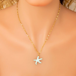 Detail showing an 18K gold plated starfish pendant with light blue oil drip on skin