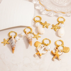 Dettaglio di orecchini dorati a tema marino con stelle marine, conchiglie e perle