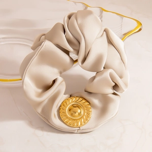 Details eines champagnerfarbenen Satin-Haargummis mit spiralförmigem Metall-Zubehör