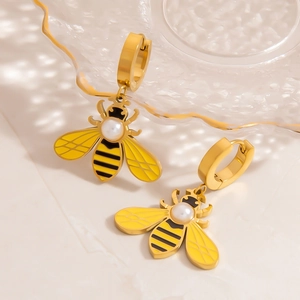 Goldene Bienenohrringe mit Perle und gelber Emaille auf einem Glastablett