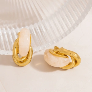 Detail view of gold titanium earrings with cream resin inlay and marble texture