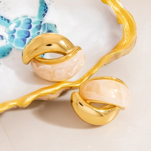 Detailed shot of gold twisted hoop earrings with marble resin on a ceramic jewelry tray