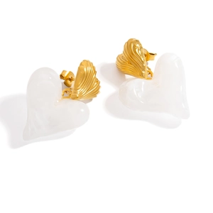 Detail of elegant gold heart earrings with white resin inlay and textured metallic finish