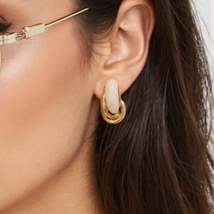 Vintage gold U-shaped earrings with pale pink oval stones on a model's ear
