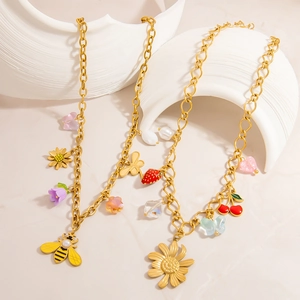Goldene Halskette mit bunten Emaille-Anhängern wie Blumen Schmetterlingen und Kirschen