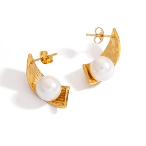 Close-up of golden textured earrings with large white pearls on a white background