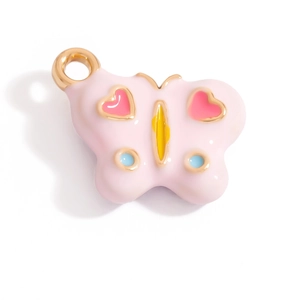 Macro detail of a pink butterfly enamel pendant with golden edges and heart motifs