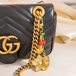 Quilted black leather shoulder bag featuring gold chain and cherry flower pearl charms