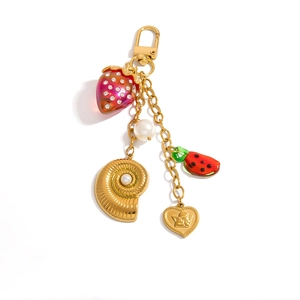 Detail of gold keychain with strawberry, pearl, shell, watermelon, and heart charms