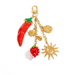 Detail of colorful charms featuring red pepper, strawberry beads, and gold shell on a keychain