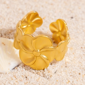 Dettaglio dell'anello a fiore di plumeria dorato con fascia regolabile su spiaggia