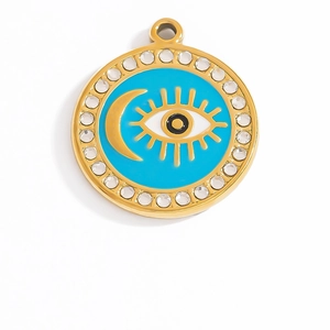 Macro view of gold evil eye pendant with blue enamel, crescent moon and crystal inlay