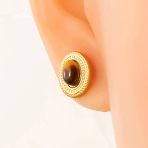 Close-up of vintage oval gold stud earrings with brown tiger eye stone on model