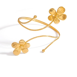 Détail d'un bracelet de bras spirale doré avec deux fleurs ciselées et fini martelé