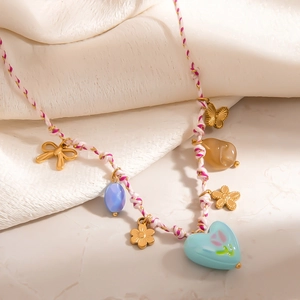 Handgewebte Kette mit goldenen Schmetterlingsanhängern und blauem Herz auf Steinbasis