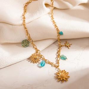 Goldene Knotenkette mit Muschel, Seestern und bunten Gänseblümchen auf Marmoroberfläche