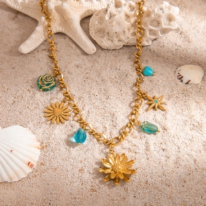 Detail von goldenen Seesternen und Muschelanhängern auf Strandsand mit Küstenelementen