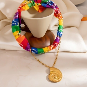 Collana bohémien in tessuto arcobaleno con ciondolo a spirale dorato su base marmo