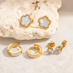Details von drei vergoldeten Edelstahl-Ohrringen mit Blumendesign und Zirkon-Steinen
