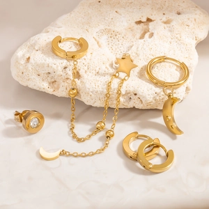 Detailansicht goldener Edelstahl-Ohrringset mit Mond- und Sternanhängern auf Stein