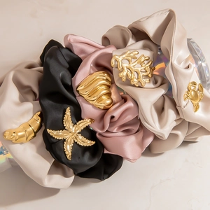 Detailaufnahme von Premium-Satin-Haargummis mit eleganten goldenen Meeres-Metallanhängern