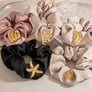 5-teiliges Set Satin-Haargummis mit goldenen Seestern-Anhängern auf Marmorhintergrund