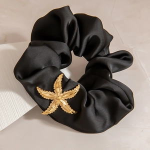 Detailansicht eines schwarzen Satin-Haargummis mit goldenem Seestern-Anhänger