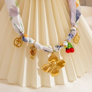 Detail of silk scarf necklace with 18K gold-plated tropical charms and floral pattern
