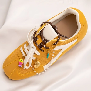 Fashionable yellow mesh sneaker with pearl chain and fish charms in a beach style