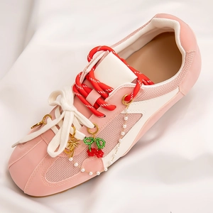 Detail of pink sneakers with cherry charm, pearl chain and coconut tree pendant