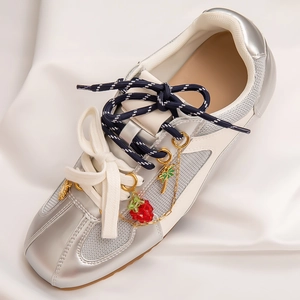 Detailed close-up of metallic silver sneakers featuring strawberry and palm tree pendants