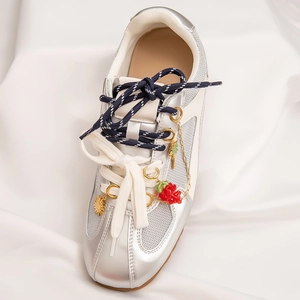 Detailed view of sneakers with silver-white mesh, double laces and DIY metal charms