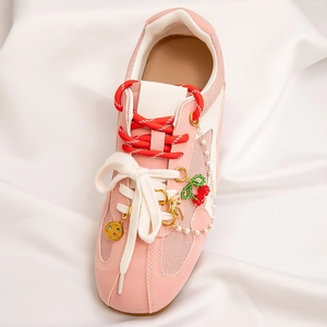 Detailed view of DIY charms with cherry pendant and pearls on pink mesh sneakers