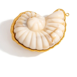 Dettaglio macro del ciondolo a nautilus con bordi placcati oro e trama a spirale crema