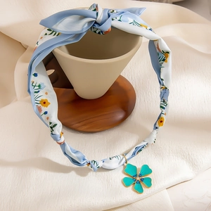 Floral print silk scarf necklace with a delicate green flower pendant in a soft layout